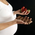 Pregnant woman with chocolate bar and strawberries. Conceptual image shot Royalty Free Stock Photo