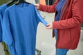 Pregnant woman chooses loose blue T-shirt in store to buy. Hands close up