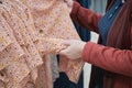 Pregnant woman chooses a loose dress in in a flower to buy. Hands close up shot