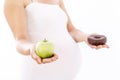 Pregnant woman choosing healthy apple over unhealthy donut Royalty Free Stock Photo