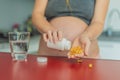 pregnant woman conscientiously takes fish oil capsules, rich in omega-3, prioritizing essential nutrients for a healthy