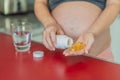 pregnant woman conscientiously takes fish oil capsules, rich in omega-3, prioritizing essential nutrients for a healthy