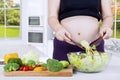 Pregnant woman cooks salad in kitchen Royalty Free Stock Photo