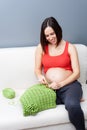 Pregnant woman crocheting at home