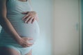 Pregnant woman cuddling belly in bedroom at home Royalty Free Stock Photo