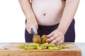 Pregnant woman cuts kiwi fruit Royalty Free Stock Photo