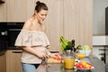 Pregnant woman cutting tomato in the kitchen Royalty Free Stock Photo