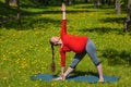 Pregnant woman doing asana Utthita trikonasana outdoors