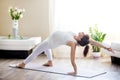 Pregnant woman doing Camatkarasana yoga pose at home