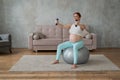 Pregnant woman doing exercises with dumbbells while sitting on a fitness ball at home. Royalty Free Stock Photo