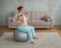 Pregnant woman doing exercises with dumbbells while sitting on a fitness ball at home. Royalty Free Stock Photo