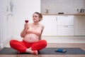 Pregnant woman doing fitness at home and looking at red wine in a glass Royalty Free Stock Photo