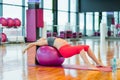 pregnant woman doing yoga on fit ball bandhasana pose in gym day side view