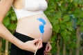 Pregnant woman draws himself on the belly with brush baby footprint. Pregnant concept. Close-up