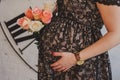 Pregnant woman in dress hugs her belly.