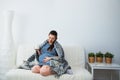 Pregnant woman drink tea and touch her belly under warm cozy plaid Royalty Free Stock Photo