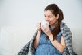Pregnant woman drink tea and under warm cozy plaid at home Royalty Free Stock Photo