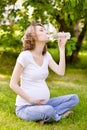 Pregnant woman drinking fresh water in the park Royalty Free Stock Photo