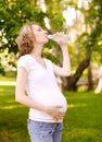 Pregnant woman drinking fresh water in the park Royalty Free Stock Photo