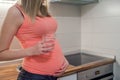 Pregnant woman drinking glass of water at home in the kitchen, B Royalty Free Stock Photo