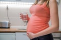 Pregnant woman drinking glass of water at home in the kitchen, Royalty Free Stock Photo