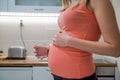 Pregnant woman drinking glass of water at home in the kitchen. H Royalty Free Stock Photo