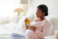 Pregnant woman drinking orange juice in bed Royalty Free Stock Photo