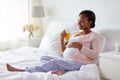 Pregnant woman drinking orange juice in bed Royalty Free Stock Photo