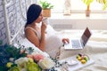 Pregnant woman drinking tea, working on laptop in bed Royalty Free Stock Photo