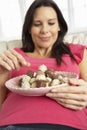 Pregnant Woman Eating Chocolates Sitting On Sofa At Home Royalty Free Stock Photo