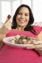 Pregnant Woman Eating Chocolates Sitting On Sofa At Home Royalty Free Stock Photo