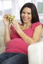 Pregnant Woman Eating Grapes Sitting On Sofa At Home Royalty Free Stock Photo