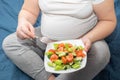 A pregnant woman is eating a healthy homemade organic fruit salad while sitting on her bed. Royalty Free Stock Photo