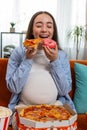 Pregnant woman eating unhealthy junk fatty fast food pizza popcorn crisp watching movie at home Royalty Free Stock Photo