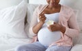 Pregnant woman eating yogurt for breakfast in bed Royalty Free Stock Photo