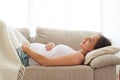 Pregnant woman embracing belly while sleeping on back