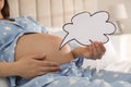 Pregnant woman with empty paper thought cloud indoors, closeup. Choosing baby name