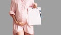 Pregnant woman with empty white paper as medical card, agreement blank. Template for text