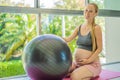 Pregnant woman exercising on fitball at home. Pregnant woman doing relax exercises with a fitness pilates ball. Against Royalty Free Stock Photo