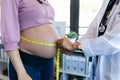 Pregnant woman exposing her belly while doctor using a measuring tape to follow the growth of the baby at a hospital Royalty Free Stock Photo