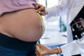 Pregnant woman exposing her belly while doctor using a measuring tape to follow the growth of the baby at a hospital Royalty Free Stock Photo