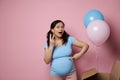 Amazed pregnant woman expecting twins, posing near pink and blue balloons flying out from a box at gender reveal party Royalty Free Stock Photo