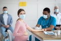 Pregnant woman in face mask getting vaccinated against Covid-19 at clinic Royalty Free Stock Photo