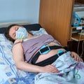 A pregnant woman in face mask gives birth in a hospital with a drip and a cardiotocograph machine. A woman on a clinic bed during Royalty Free Stock Photo