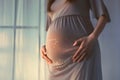 Pregnant woman feeling happy at home while taking care of her child. The young expecting mother holding baby in pregnant belly.