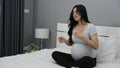 Pregnant woman feeling nauseous on bed