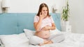 Pregnant woman feeling sick with nausesa sitting on bed at morning. Intoxication during pregnancy
