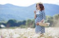 Pregnant woman in field with basket of white daisies Royalty Free Stock Photo