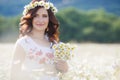 A pregnant woman in a field with a bouquet of white daisies Royalty Free Stock Photo