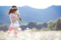 A pregnant woman in a field with a bouquet of white daisies Royalty Free Stock Photo